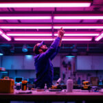 A photograph of a well-lit workspace featuring a lighting contractor installing or adjusting fluorescent fixtures