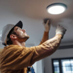 A photograph of a lighting contractor expertly installing recessed led can lights in a modern home setting