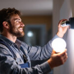 A photograph of a lighting contractor installing bright led light bulbs in a modern home setting