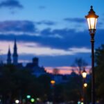 A photograph of a beautifully designed three-light lamp post in an urban setting during twilight