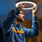 A photograph of a skilled lighting contractor expertly installing or adjusting a halo can light in a stylish interior setting