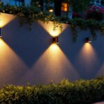 A photograph of a beautifully lit outdoor wall featuring various styles of wall-mounted lighting fixtures in a serene evening setting