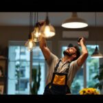 A photograph of a lighting contractor expertly installing or adjusting various stylish light fixtures in a beautifully designed home interior