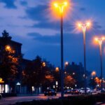 A photograph of a well-lit urban scene showcasing a row of sleek steel light poles illuminating a bustling street at dusk