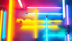 A photograph of a vibrant display of various coloured fluorescent tube lights arranged artistically in a well-lit workspace