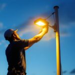 A photograph of a lighting contractor expertly installing or adjusting outdoor lighting on a flagpole at dusk