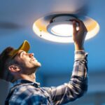 A photograph of a skilled contractor installing an 8-inch led recessed light in a modern ceiling