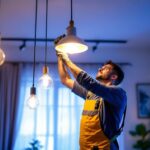 A photograph of a skilled lighting contractor installing stylish led hanging lights in a modern interior space