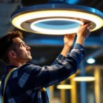 A photograph of a lighting contractor skillfully installing a modern ufo light fixture in a commercial space