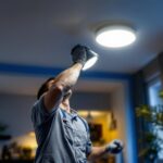 A photograph of a lighting contractor expertly installing recessed lights in a modern home setting
