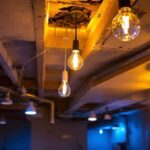 A photograph of a well-lit unfinished basement ceiling showcasing various lighting options