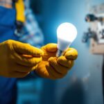 A photograph of a lighting contractor expertly installing a led light bulb into a modern socket