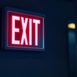 A photograph of a battery-operated exit sign illuminated in a dimly lit environment