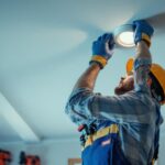 A photograph of an electrician or lighting contractor installing ic-rated pot lights in a residential ceiling