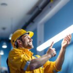 A photograph of a lighting contractor installing a 4ft tube light in a commercial space
