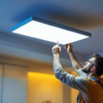 A photograph of a lighting contractor installing or adjusting a sleek ceiling lighting panel in a modern interior space