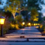 A photograph of a lighting contractor installing plug-in pathway lights in a beautifully landscaped outdoor setting during twilight