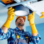 A photograph of a lighting contractor installing a light fixture box in a ceiling