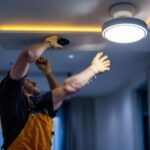 A photograph of a lighting contractor installing led recessed dimmable lights in a modern home setting