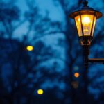 A photograph of a modern electric lamp post illuminating a well-lit urban street at dusk