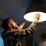 A photograph of a lighting contractor installing a modern ceiling light fixture in a stylish interior space
