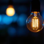 A photograph of a close-up shot of a flickering light bulb in a dimly lit room