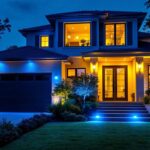 A photograph of a well-lit residential exterior featuring striking blue led lights accentuating architectural details