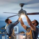 A photograph of a lighting contractor expertly installing a ceiling fan light kit in a stylish home interior