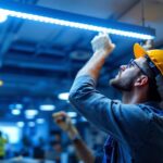 A photograph of a lighting contractor installing or adjusting overhead led lights in a modern workspace
