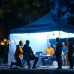 A photograph of a solar tent lamp illuminated in a nighttime outdoor setting