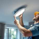 A photograph of a skilled lighting contractor installing an 8-inch recessed light fixture in a modern home
