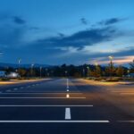 A photograph of a well-lit parking lot at dusk