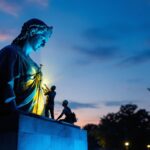 A photograph of a well-lit statue at dusk