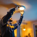 A photograph of a lighting contractor skillfully installing a recessed can led retrofit in a modern home