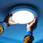 A photograph of a skilled electrician installing a led conversion kit in a modern recessed lighting fixture