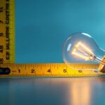 A photograph of capture a photograph of an a19 light bulb next to a measuring tape or ruler