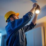 A photograph of a skilled lighting contractor expertly installing or adjusting a spot flood light in a residential or commercial setting