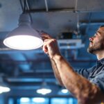 A photograph of a lighting contractor expertly installing a 400w metal halide led replacement in a commercial space