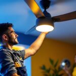 A photograph of a lighting contractor installing a modern replacement light fixture in a stylish ceiling fan
