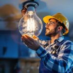 A photograph of a lighting contractor carefully installing a halogen lamp in a residential setting