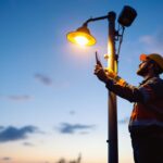 A photograph of a lighting contractor inspecting a well-designed light pole installation at dusk