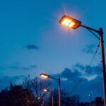 A photograph of a well-lit electric light post at dusk