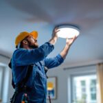 A photograph of a skilled lighting contractor installing a recessed can light in a modern home setting