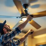 A photograph of a skilled lighting contractor installing or adjusting a stylish ceiling fan with metal blades in a modern interior setting