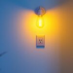 A photograph of a stylish light fixture installed above a modern electrical outlet