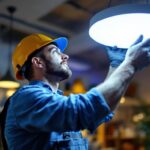A photograph of a lighting contractor efficiently installing a circular led light fixture in a modern workspace