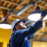 A photograph of a lighting contractor expertly installing or adjusting high hat light covers in a modern interior space