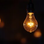 A photograph of a close-up shot of a flickering light bulb in a dimly lit room