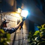 A photograph of a lighting contractor expertly installing floodlight leds in a residential or commercial setting
