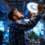 A photograph of a lighting contractor skillfully installing or adjusting hid lighting fixtures in a modern workspace